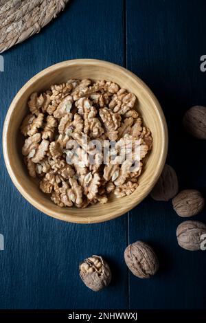 Walnusskernhälften in einer Holzschüssel. Nahaufnahme, von oben, Makro-Food-Foto. Stockfoto