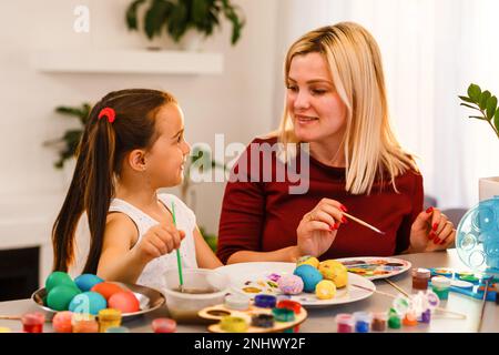 Osterfamilientraditionen. Familien malen Eier am Küchentisch Stockfoto