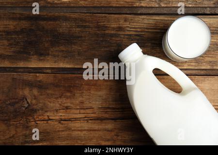 Gallonflasche und ein Glas Milch auf einem Holztisch, flach liegend. Platz für Text Stockfoto