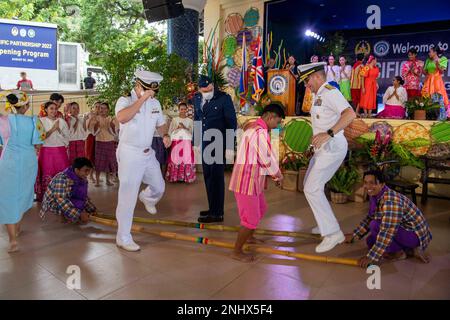 PUERTO PRINCESA, Philippinen (3. August 2022) – Hinten ADM. Mark Melson, Befehlshaber, Task Force 73 (CTF 73), rechts, Und LT. Zachary Coffel, Pacific Partnership 2022 (PP22) Verantwortlicher philippinischer Planungsteam-Offizier, führt den traditionellen philippinischen Volkstanz Tinikling während der philippinischen Eröffnungszeremonie PP22 im Mendoza Park mit kulturellen Künstlern auf. Die Pazifikpartnerschaft ist die größte multinationale Mission zur Vorbereitung auf humanitäre Hilfe und Katastrophenhilfe, die jährlich im Indo-Pazifik durchgeführt wird. Sie ist seit 17. Jahren Teil der Partnerschaft. Stockfoto