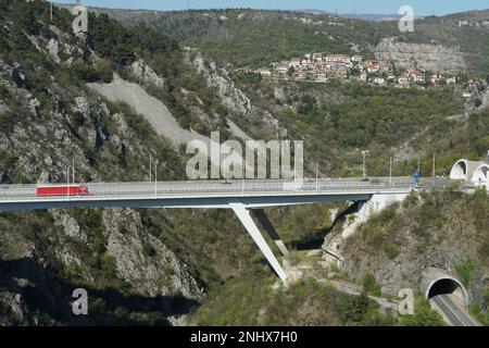 Tunnel und Brücke über den Canyon in Rijeka, Kroatien beobachtet vom Schloss Trsat während des Sommertags. Auf der Straße fährt ein rotes Auto vorbei. Stockfoto