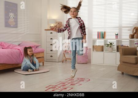 Süße kleine Mädchen, die zu Hause Hopscotch spielen Stockfoto