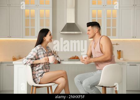 Glückliches Paar mit Schlafanzug beim Frühstück am Tisch in der Küche Stockfoto