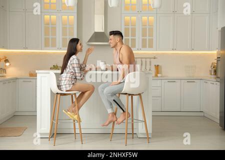 Glückliches Paar mit Schlafanzug beim Frühstück am Tisch in der Küche Stockfoto