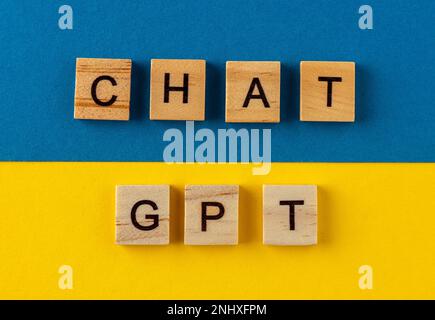 ChatGPT-Hintergrund. Wörter in Holzbuchstaben. Chatten Sie mit KI oder künstlicher Intelligenz von OpenAI. Satz auf blau und gelb. Ukrainische Farbe Stockfoto
