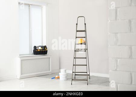 Leiter, Dekorationswerkzeuge und Kiste mit Instrumenten im Zimmer Stockfoto