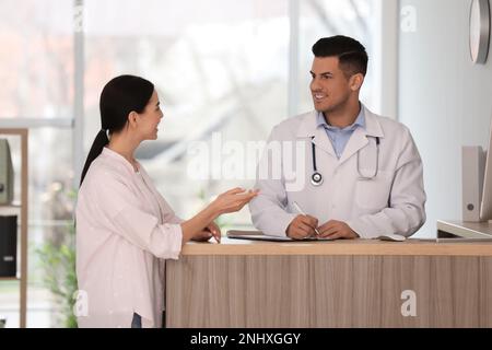 Arzt, der mit dem Patienten an der Rezeption im Krankenhaus arbeitet Stockfoto