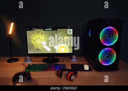 Moderner Computer und RGB-Tastatur auf Holztisch im Zimmer Stockfoto