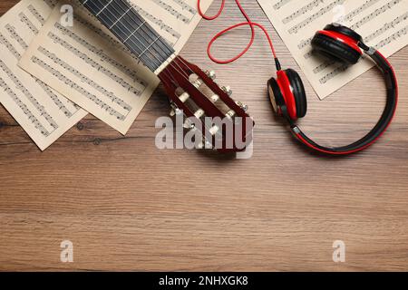 Komposition mit Gitarre und Noten auf Holztisch, flach liegend. Platz für Text Stockfoto