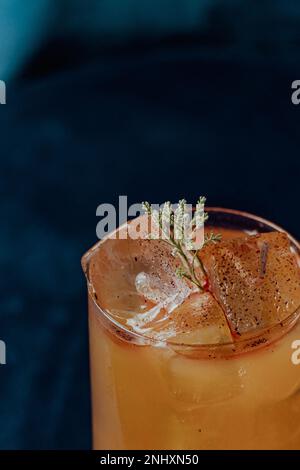 Eine Nahaufnahme Orangencocktail garniert mit einem Thymianzweig Stockfoto