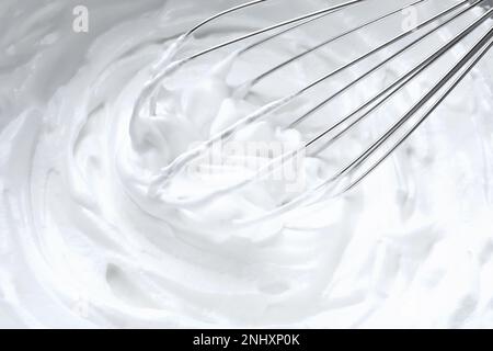 Weiße Sahne mit Schneebesen, Nahaufnahme Stockfoto