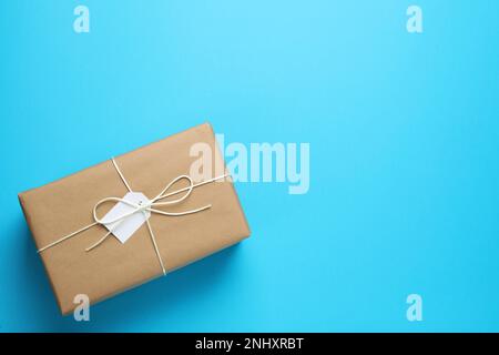 Paket in Kraftpapier eingewickelt mit Anhänger auf hellblauem Hintergrund, Draufsicht. Platz für Text Stockfoto