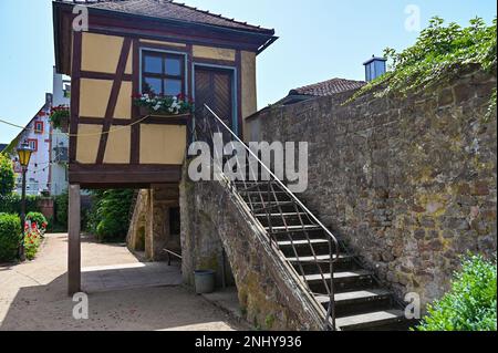 Treppe auf einer alten Steinmauer eines Schlosses im Sonnenlicht mit einem Fachwerkhaus Stockfoto