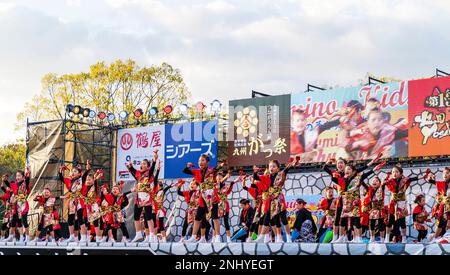 Japanische Kindermannschaft Yosakoi-Tänzer, die Naruko tanzen und Fans auf der Bühne des Kyusyu Gassai Festivals in Kumamoto halten. Stockfoto