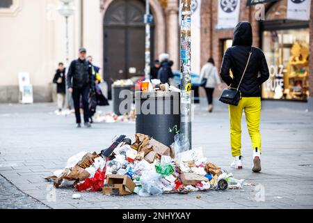 München, Deutschland. 22. Februar 2023. Am Marienplatz ist während eines zweitägigen Warnstreiks der Münchner Straßenreiniger ein überlaufender Mülleimer zu sehen. Aufgrund des Streiks der Münchner Straßenreiniger wurde Müll am Viktualienmarkt nach den Feierlichkeiten für den Shrove-Dienstag zurückgelassen. Kredit: Matthias Balk/dpa/Alamy Live News Stockfoto