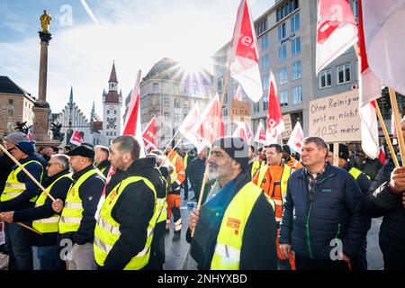 München, Deutschland. 22. Februar 2023. Teilnehmer einer Streiksitzung der Münchner Straßenreiniger stehen mit Verdi-Flaggen auf dem Marienplatz als Teil eines zweitägigen Warnstreiks. Kredit: Matthias Balk/dpa/Alamy Live News Stockfoto