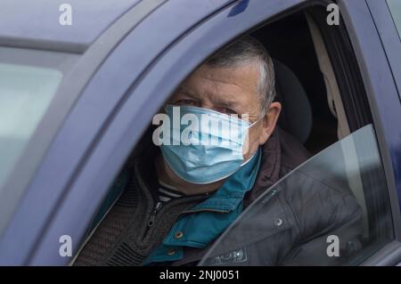 Porträt eines kaukasischen Senior-Fahrers, der eine Maske trägt, während er in seinem Auto sitzt Stockfoto