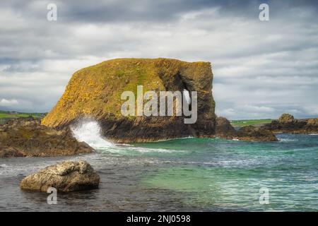 Wunderschöne Küstenfelsformation, Elefantenfelsen mit planschenden Wellen und türkisfarbenem Wasser auf einem Wild Atlantic Way in Country Antrim, Nordirland Stockfoto