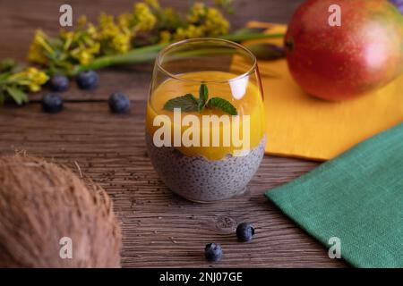 panna Cotta mit Mango und Chiasamen, auf einem Holzbrett Stockfoto