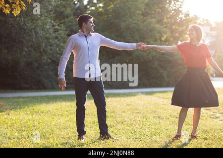 Ein verliebtes junges Paar tanzt frei im Park im Nachmittagssonnenschein. Stockfoto