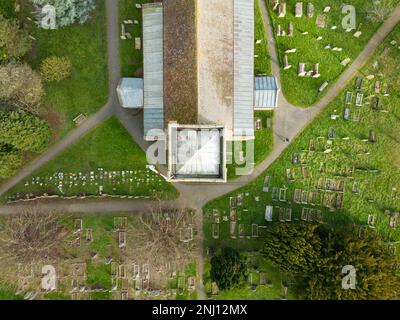 Draufsicht auf einen hohen Kirchturm mit kunstvoll verzierten Flügeln und Blei. Gräber sind unten zu sehen. Stockfoto