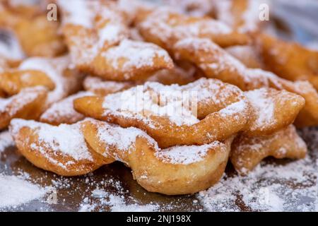 Gebratene Karnevalspaste, Streifen gebratener Teig, die typischerweise am Karneval hergestellt werden, mit Puderzucker bedeckt, Nahaufnahme Stockfoto