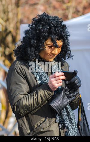 Ein Mann, der während Uzgavenes, einem litauischen Volksfest während des Karnevals, 7. Woche vor Ostern, mit einer hässlichen, gruseligen Maske auf das Smartphone schaut Stockfoto