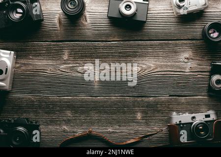 Fotografischer Konzepthintergrund mit verschiedenen alten Filmfotokameras auf einem Grunge-Holztisch. Leerer Platz für Ihre SMS Stockfoto