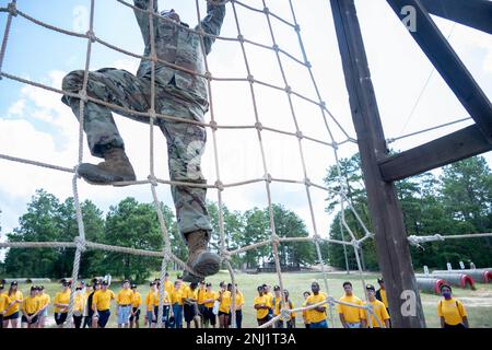 Staff Sgt. Michael Vork, ein Ausbilder des 3. Bataillons, 60. Infanterie-Regiment, demonstriert, wie man das Hindernis im Frachtnetz auf dem Kurs Fit to Win II am 4. August befolgt. Vork begleitete 38 Kadetten des Navy Junior Reserve Officer Training Corps von der South Aiken High School, S.C., durch die Anlage, um ihnen zu zeigen, wie Fort Jackson Zivilisten in Soldaten verwandelt. Stockfoto