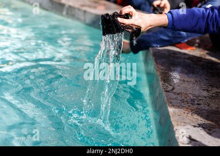 München, Deutschland. 22. Februar 2023. Eine Frau wäscht ihre Handtasche im Fischbrunnen am Marienplatz während der traditionellen Handtaschenwäsche. Kredit: Matthias Balk/dpa/Alamy Live News Stockfoto