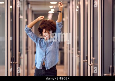 Fröhliche Junge Geschäftsfrau Feiert Tanzen Entlang Des Korridors In Modern Office Stockfoto
