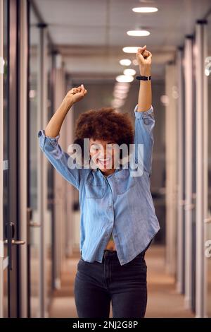 Fröhliche Junge Geschäftsfrau Feiert Tanzen Entlang Des Korridors In Modern Office Stockfoto
