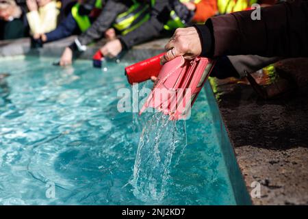 München, Deutschland. 22. Februar 2023. Eine Frau wäscht ihre Handtasche im Fischbrunnen am Marienplatz während der traditionellen Handtaschenwäsche. Kredit: Matthias Balk/dpa/Alamy Live News Stockfoto