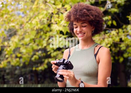 Junge Frau im Freien mit DSLR-Kamera Fotos im Stadtpark machen Stockfoto