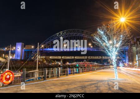 Newcastle upon Tyne, UK Quayside bei Nacht. Sie sehen die Tyne Bridge, die Swing und die High Level Brücken beleuchtet und Reflexionen der Lichter auf dem Fluss. Stockfoto