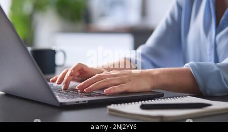 Nahaufnahme Einer Frau, Die Am Schreibtisch Auf Der Laptop-Tastatur Tippt Stockfoto