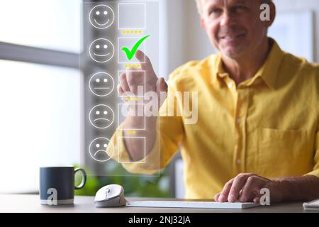 Mann, Der Einen Computer Mit Grafiküberlagerung Verwendet, Um Eine Positive Online-Prüfung Zu Hinterlassen Stockfoto