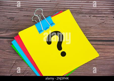 Fragezeichen auf gelbem Notizblock mit Holzhintergrund. Motivationskonzept. Stockfoto
