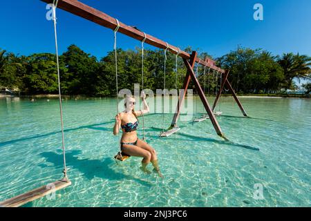 Wunderschöne weibliche Touristen, die sich auf einer Schaukel in Laguna Bacalar in Mexiko während des Kajakausflugs entspannen. Stockfoto