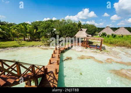 Wunderschöne Landschaft mit jungen Frauen, die sich während des Kajakausflugs auf einem hölzernen Pier in Laguna Bacalar in Mexiko entspannen. Stockfoto