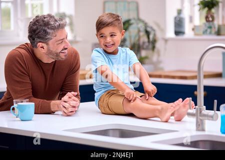 Familie Mit Vater In Der Küche, Sohn Sitzt An Der Theke Stockfoto