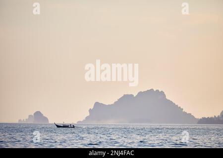 Traditionelles Langschwanz in Silhouette in der Nähe tropischer Inseln bei Sonnenuntergang in der Andamanensee, Südthailand Stockfoto