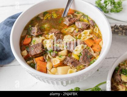 Rindernudelsuppe mit durchsichtiger Brühe, Wurzelgemüse und Pasta in einer Schüssel. Deutsche Küche Stockfoto