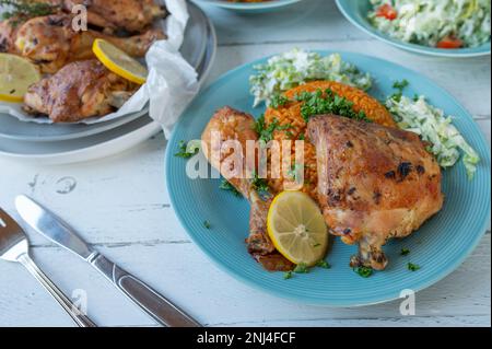 Gebackenes Hähnchen mit Tomatenreis und Salat auf Tellern. Köstliches mediterranes Abendessen oder Mittagessen im Sommer Stockfoto