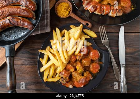 Currywurst oder Currywurst mit pommes Frites auf einem Holztisch. Stockfoto