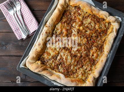 Hackfleisch-Pizza mit Käse auf einem Backblech isoliert auf dunklem Holzhintergrund Stockfoto