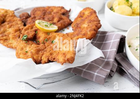 Teller mit frisch gebratenem Schnitzel in der Pfanne auf dem Küchentisch Stockfoto