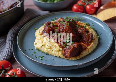 Schweineragout mit cremiger Polenta auf einem Teller. sonntags oder an Feiertagen hausgemachtes Abendessen oder Mittagessen Stockfoto