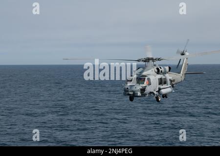 Ein Royal Danish Navy MH-60R Hubschrauberpilot, der an HDMS Triton Waves befestigt ist, während er während des Betriebs Nanook 2022, Nordatlantik, 5. August 2022, an der Hafenseite von USCGC Bear (WMEC 901) vorbeifliegt. Operation Nanook ist eine multinationale Militärübung, die die Fähigkeiten der Vereinigten Staaten und der Partnerländer zur Förderung gemeinsamer maritimer Ziele in arktischen Umgebungen hervorhebt. Stockfoto