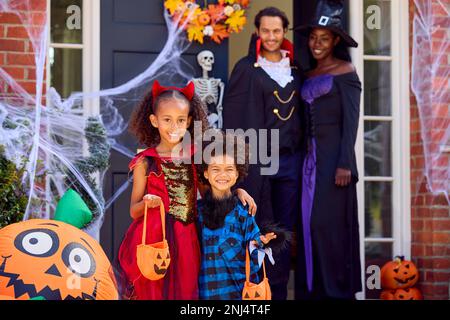 Porträt Der Familie, Die Sich Für Halloween Verkleidet, Vor Dem Haus Bereit Für Süßes Oder Saures Stockfoto